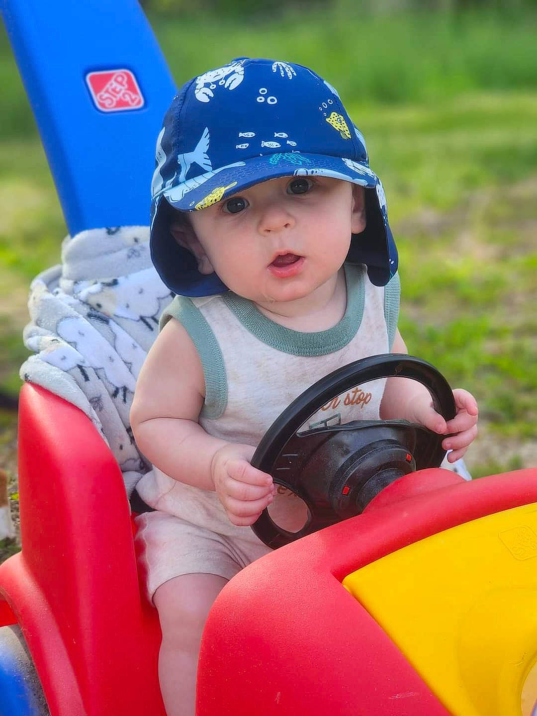 Bryar joined the competition — help win amazing prizes! baby_toddler_clothing, baseball_cap, cap, child, electric_blue, facial_expression, fashion_accessory, fun, grass, happy, headgear, headwear, helmet, leisure, person, personal_protective_equipment, play, recreation, sitting, sports_gear