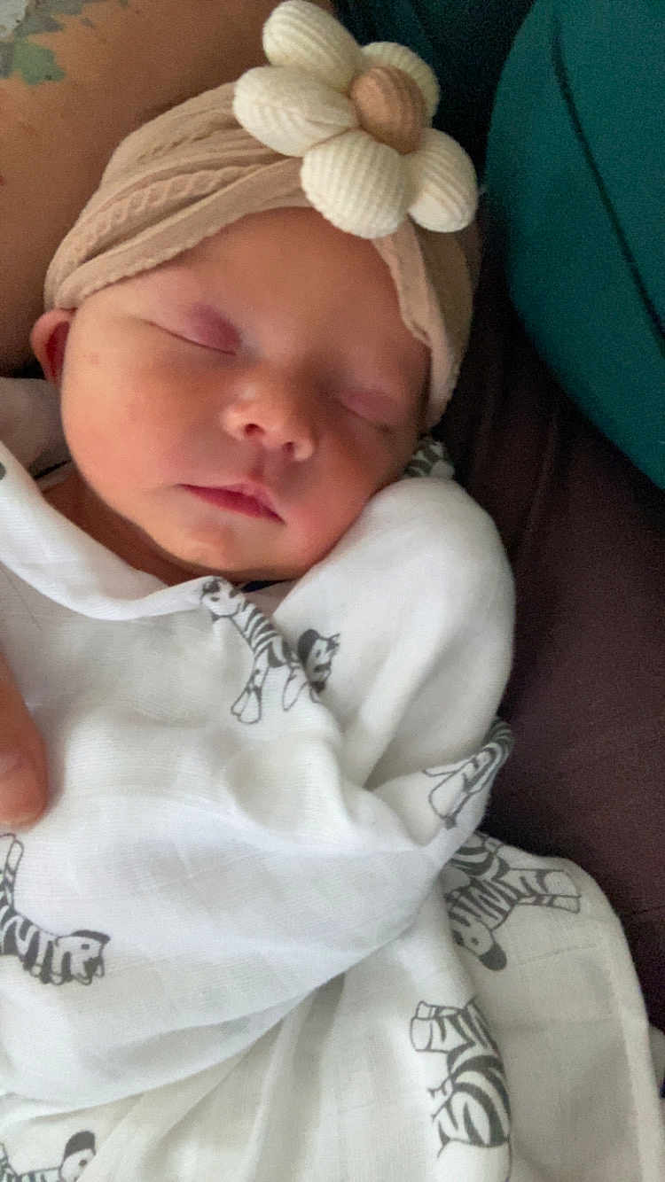 Lyra is registered to the contest to win money with this photo: baby, sleeping, blanket, headband, flower, infant, closeup, cozy, soft, cute, wrapped, peaceful, child, newborn, person, indoors, fabric, zebra_print, resting, portrait