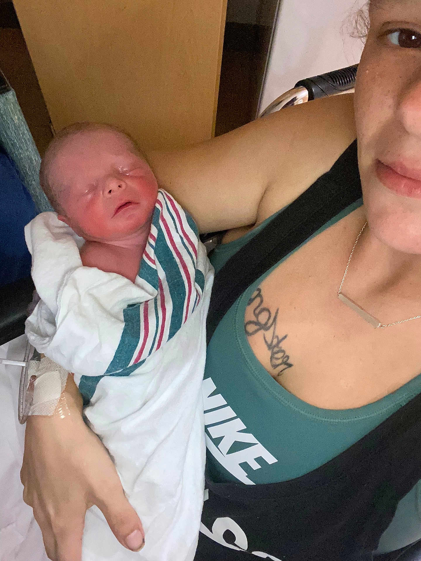Colton is registered to the contest to win money with this photo: newborn, baby, woman, hospital, blanket, swaddled, sleeping, tattoo, necklace, clothing, hand, person, portrait, indoor, comfort, care, mother, rest, closeup, skin