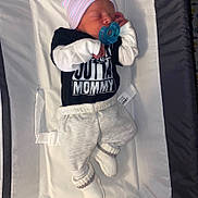 Colton joined the competition — help win amazing prizes! baby, baby_bed, black_shirt, booties, child, clothing, cozy, cute, hat, indoor, infant, lying_down, mittens, newborn, pacifier, resting, sleeping, soft_surface, striped_hat, white_pants
