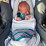 baby, blanket, car_seat, child, cozy, cute, head_support, indoors, infant, newborn, pacifier, peaceful, resting, safety, seatbelt, sleeping, small_hands, striped_blanket, warning_label, wrapped