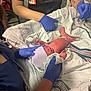 newborn, baby, medical_staff, hospital, gloves, blanket, hat, umbilical_cord, patient_care, healthcare, person, medical_equipment, bed, treatment, nursery, clinic, newborn_care, delivery_room, human, infant