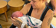 Colton is registered to the contest to win money with this photo: newborn, mother, hospital, wheelchair, tattoos, baby, woman, holding, blanket, indoor, medical, love, family, parent, rest, arm, person, smile, face, seated