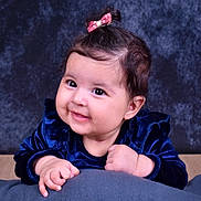 Amira Naima a rejoint le concours — aidez-le/la à gagner de superbes lots ! adorable, baby, child, cushion, cute, dark_background, face, hands, happy, head, indoor, infant, person, pink_bow, portrait, smiling, soft_toy, studio_photo, velvet_clothing, young_child