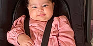 Amira Naima a rejoint le concours — aidez-le/la à gagner de superbes lots ! baby, black_car_seat, bow, car_seat, child, clothing, cute, face, hand, harness, indoor, infant, person, pink_dress, portrait, seatbelt, sitting, smile, toddler, toy
