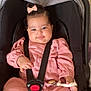 baby, child, car_seat, pink_dress, bow, smile, harness, black_car_seat, cute, infant, toddler, clothing, seatbelt, indoor, person, portrait, sitting, toy, hand, face