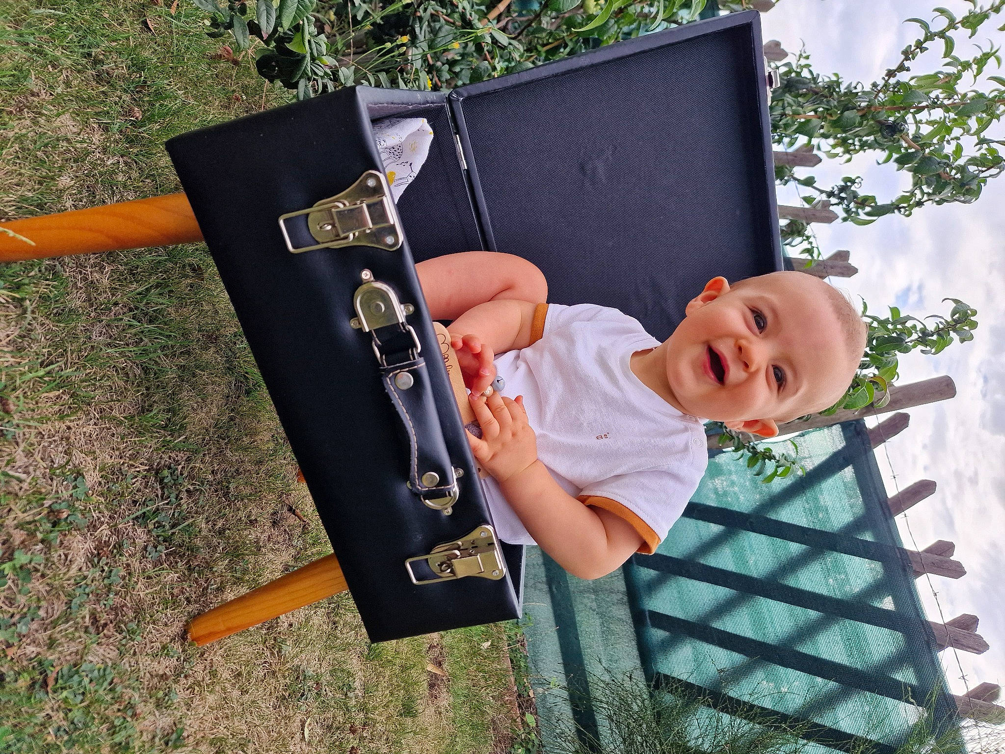 Robin a rejoint le concours — aidez-le/la à gagner de superbes lots ! baby, baby_laughing, baby_toddler_clothing, blackboard, chalk, child, easel, grass, happy, leisure, office_supplies, person, plant, sitting, sleeve, smile, t_shirt, toddler, tree