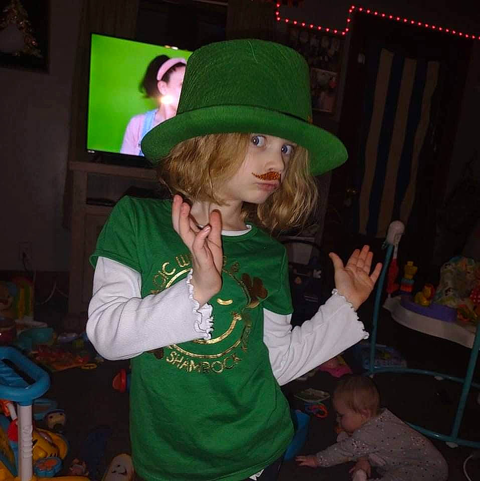 Gracey is registered to the contest to win money with this photo: cap, chair, christmas, christmas_eve, christmas_ornament, costume_hat, couch, event, fashion_accessory, fun, hat, holiday, party, person, room, saint_patricks_day, sun_hat, t_shirt, television, toddler