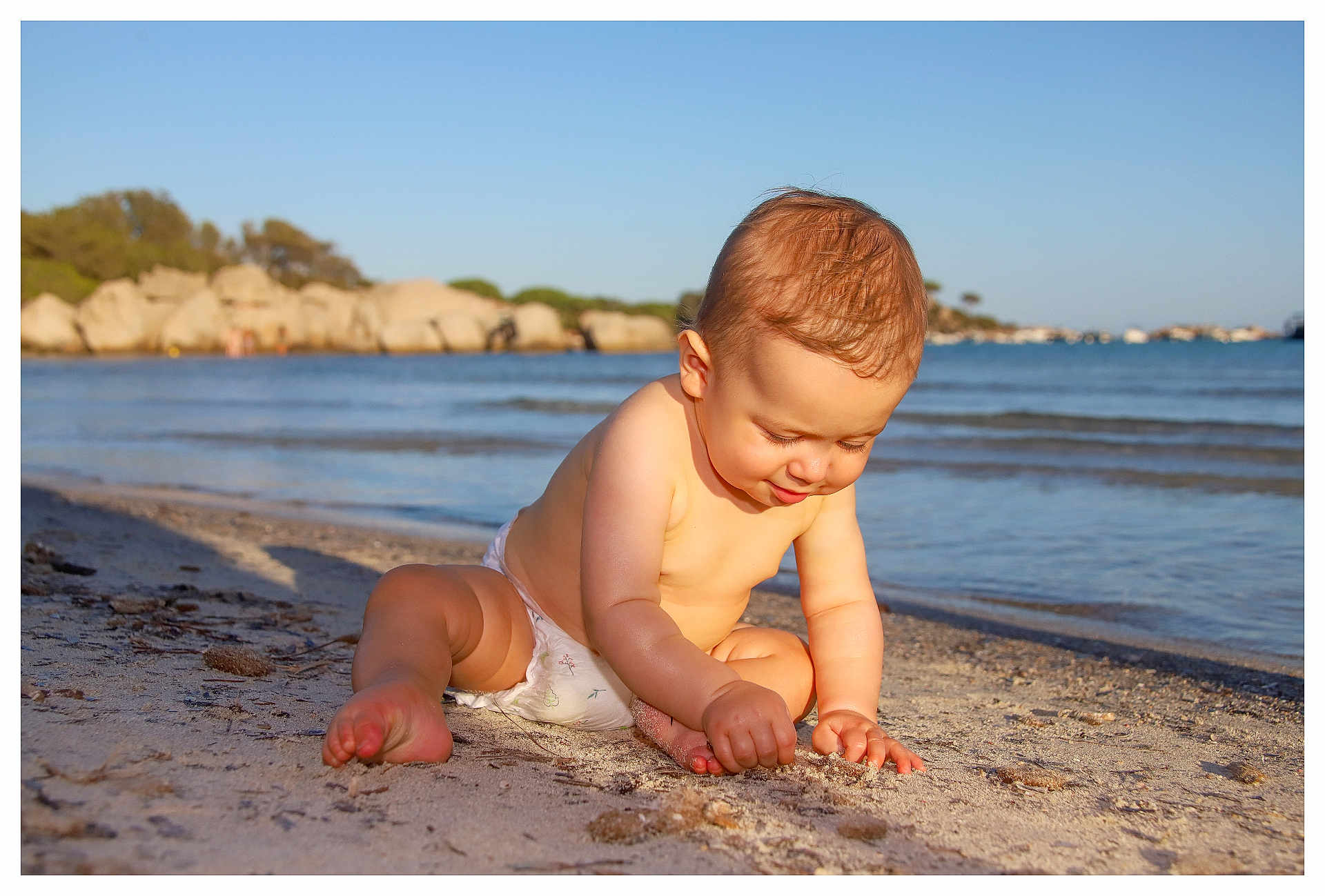 Maé a rejoint le concours — aidez-le/la à gagner de superbes lots ! baby, child, diaper, beach, sand, water, sea, waves, sunlight, outdoor, nature, sky, rock, shoreline, barefoot, toddler, playing, summer, vacation, happy
