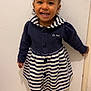 boots, child, clothing, curly_hair, cute, door, floor, full_body, girl, hair_bows, happy, indoors, navy_blue, person, portrait, smiling, standing, striped_dress, toddler, white_background