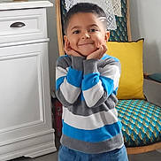 Nolan a rejoint le concours — aidez-le/la à gagner de superbes lots ! blue, boy, cabinet, casual_clothing, chair, child, cute, floor_tiles, gray, happy, home, indoors, jeans, portrait, smiling, standing, striped_sweater, vintage_furniture, white, yellow_cushion