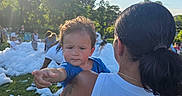 Leo joined the competition — help win amazing prizes! adult, being_held, blue_sky, bubble_party, child, crowd, curious, family, foam, grass, outdoor, parent, park, portrait, reaching, summer, sunlight, tattoo, toddler, trees