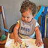 baby, bib, birthday, brown_hair, cake, celebration, child, curly_hair, eating, food, high_chair, indoor, messy, party, portrait, serious, smiling, streamers, table, toddler