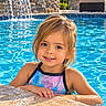 child, girl, swimming_pool, swimmer, smiling, portrait, outdoor, summer, water, waterfall, wet_hair, swimsuit, poolside, sunlight, backyard, stone, fountain, relaxation, happy, vacation
