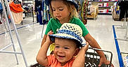 Ellie joined the competition — help win amazing prizes! baby, children, department_store, family, fashion, green_shirt, happy, indoor, matching_hats, older_child, orange_shirt, portrait, retail, shopping_cart, sibling, sitting, smiling, store_aisle, sunhat, toddler