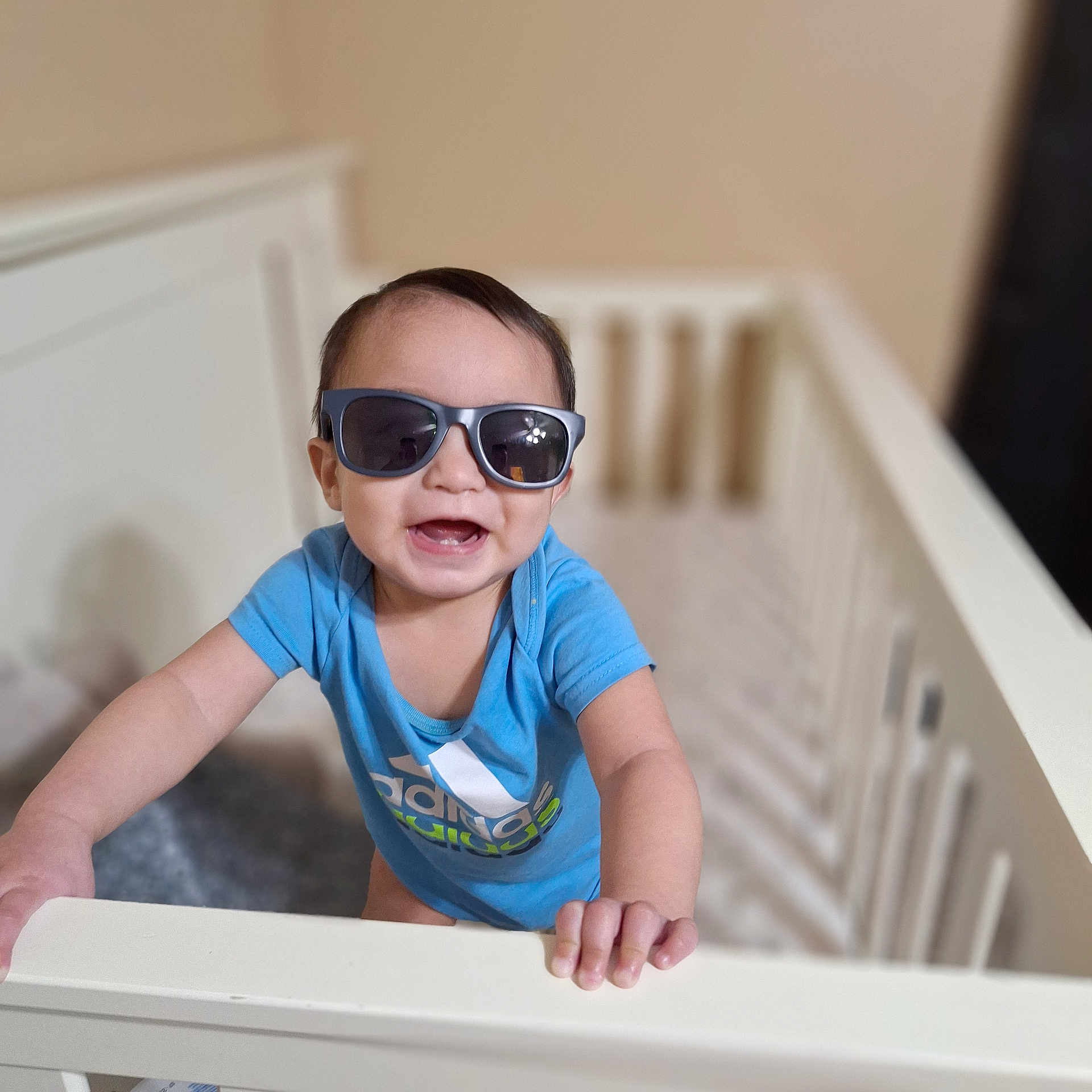 Legend joined the competition — help win amazing prizes! baby, child, sunglasses, crib, blue_shirt, smiling, indoor, person, infant, happy, hands, short_hair, head, cute, standing, furniture, clothing, playpen, portrait, young