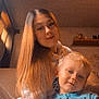 child, woman, indoor, pajamas, long_hair, portrait, cozy, family, candid, smile, blond, young, casual_clothing, relaxed, home, sitting, face, toddler, two_people, warm_lighting