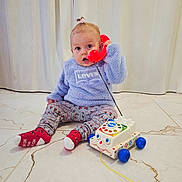Abby participe au concours pour gagner de l'argent avec cette photo : blue, child, curtains, cute, expression, floor, hair_tie, indoor, leggings, levis, patterned, playtime, pull_toy, red, seated, smiling_toy, socks, sweater, toddler, toy_phone