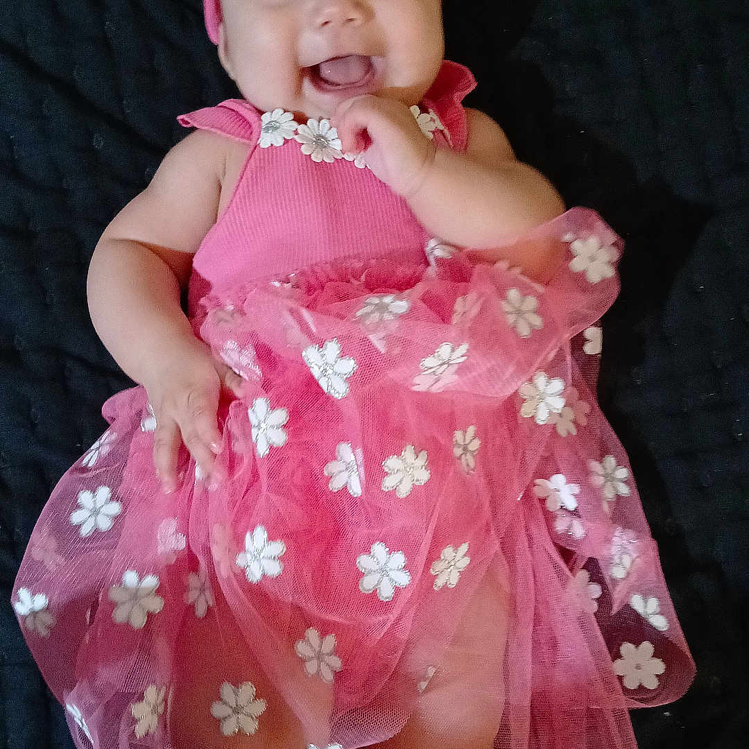 Susana joined the competition — help win amazing prizes! baby, cheerful, child, close_up, cute, dark_background, floral_pattern, happy, headband, indoor, infant, joyful, lying_down, pink_dress, portrait, small_hands, smiling, soft_lighting, tulle_skirt, white_socks
