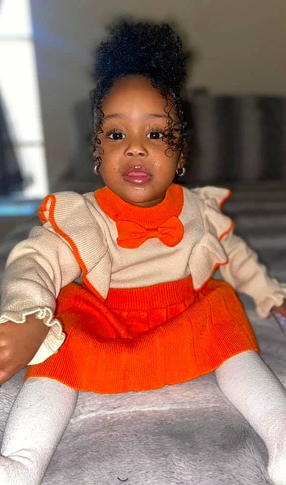 Cori joined the competition — help win amazing prizes! afro, baby_toddler_clothing, chair, cheek, child, dress, face, fashion_design, hair, happy, head, human_leg, person, sitting, skin, sleeve, sock, thigh, toddler, trunk
