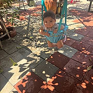 Daniel joined the competition — help win amazing prizes! baby, child, infant, swing, playground, outdoor, patio, tiles, sunlight, shadows, plants, garden, seated, hanging, portrait, face, short_hair, clothing, play_equipment, daytime