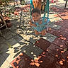 baby, child, infant, swing, playground, outdoor, patio, tiles, sunlight, shadows, plants, garden, seated, hanging, portrait, face, short_hair, clothing, play_equipment, daytime