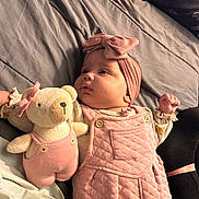 Layla is registered to the contest to win money with this photo: baby, infant, pink_clothing, headband, plush_toy, teddy_bear, bed, blanket, soft_toy, child, cute, portrait, indoor, person, sleepwear, fabric, hand, face, cozy, resting