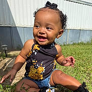 Emory is registered to the contest to win money with this photo: toddler, child, smiling, outdoor, grass, flower_print, denim_shorts, black_shoes, curly_hair, bow, sunlight, happy, skin, person, sitting, nature, daylight, casual_clothing, portrait, baby