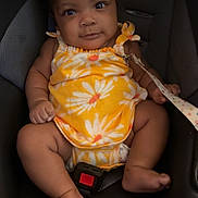 Alaia joined the competition — help win amazing prizes! baby, child, car_seat, yellow_clothing, onesie, bow, infant, seatbelt, cute, smiling, indoors, sitting, young_child, face, skin, foot, hand, straps, safety, portrait