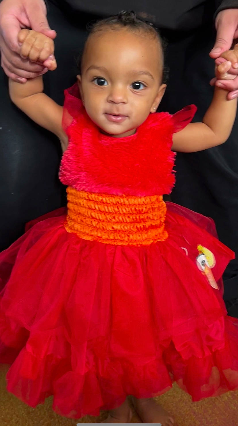 Cassidy is registered to the contest to win money with this photo: arm, baby_toddler_clothing, cheek, child, dress, face, facial_expression, gesture, hairstyle, happy, magenta, one_piece_garment, organ, person, pink, red, shoulder, skin, sleeve, toddler