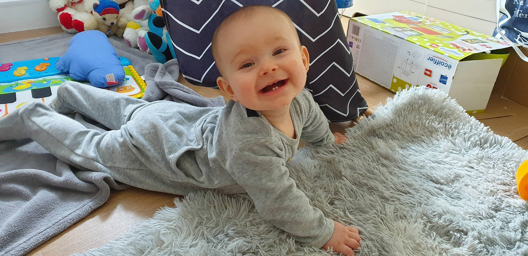 Alaric a rejoint le concours — aidez-le/la à gagner de superbes lots ! baby, baby_toddler_clothing, carton, child, comfort, face, floor, flooring, fun, happy, head, joy, package_delivery, person, play, room, shipping_box, sitting, skin, smile