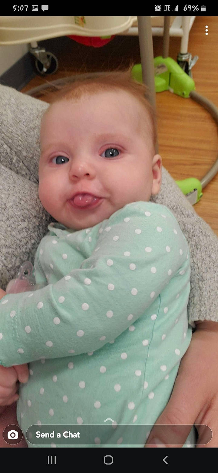Braylee is registered to the contest to win money with this photo: baby, baby_toddler_clothing, cheek, comfort, eye, facial_expression, finger, happy, head, human_body, iris, nose, organ, outerwear, person, pink, skin, sleeve, smile, textile