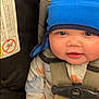 baby, blanket, blue_hat, car_seat, child, close_up, clothing, cozy, cute, face, headwear, indoor, infant, north_face, portrait, safety, seatbelt, smiling, straps, warm