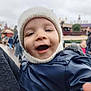 Mylo participe au concours pour gagner de l'argent avec cette photo : child, baby, toddler, face, beanie, hat, winter_jacket, coat, smile, open_mouth, closeup, portrait, outdoor, amusement_park, blurred_background, parent_arm, zipper, candid, joyful, cold_weather