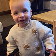 Mylo a rejoint le concours — aidez-le/la à gagner de superbes lots ! child, toddler, sweater, fox_pattern, remote_control, balloon, living_room, table, carpet, smile, eyes, blond_hair, cozy, furniture, fireplace, toy, indoor, portrait, curious, standing