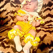 Annabella joined the competition — help win amazing prizes! baby, blanket, bonnet, child, comfortable, cozy, cute, frilly_socks, happy, indoor, infant, person, portrait, sitting, skin, smiling, soft_texture, tiger_print, yellow_clothing, young_child