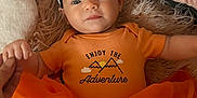 Annabella is registered to the contest to win money with this photo: baby, infant, orange_clothing, headband, bow, holding_hand, lying_down, soft_texture, blanket, cute, portrait, child, tutu_skirt, daisy_pattern, smiling, face, person, small_earring, indoor, adorable