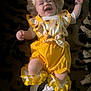 Annabella is registered to the contest to win money with this photo: baby, blanket, cheerful, child, cute, happy, hat, indoor, infant, lying_down, playful, portrait, ruffles, small_feet, small_hands, smiling, socks, soft_texture, sunflower_pattern, yellow_clothing