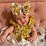 Annabella is registered to the contest to win money with this photo: baby, child, smiling, headband, flower, gold, white, dress, sparkle, sequin, embroidery, cute, portrait, sitting, pink_background, fabric, ruffle, hand, happy, infant
