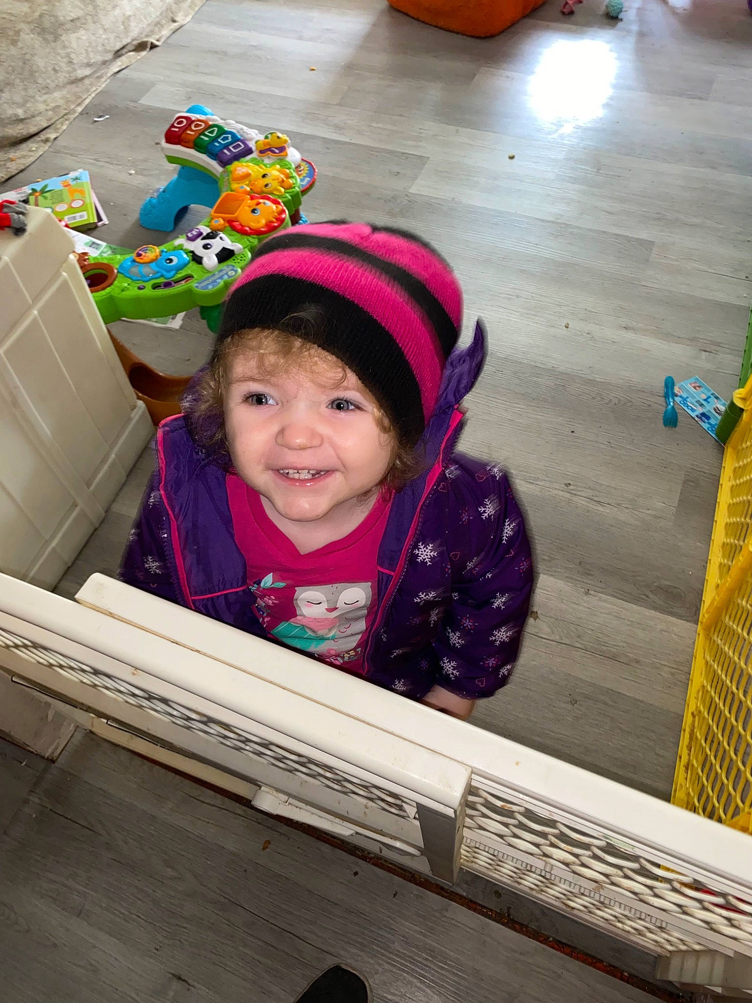 Guinevere joined the competition — help win amazing prizes! beanie, cap, child, facial_expression, flooring, fun, happy, headwear, jacket, joy, leisure, magenta, person, play, product, purple, recreation, sitting, smile, toddler