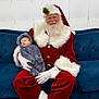 santa_claus, baby, infant, sleeping, costume, red_suit, white_fur, glasses, beard, couch, blue_couch, indoor, festive, holiday, christmas, child, person, white_gloves, smiling, cozy