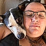 black_and_white_dog, black_tank_top, chain_necklace, close_up, companion, couch, dog, face, friendly, glasses, human_face, indoor, person, pet, piercing, relaxed, resting, sleeping_dog, snuggling, tattoo