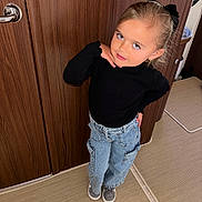 Romy a rejoint le concours — aidez-le/la à gagner de superbes lots ! child, girl, posing, black_top, blue_jeans, indoor, carpet, wooden_door, hand_on_chin, casual_clothing, smiling, standing, hair_bow, footwear, expression, portrait, person, fashion, cute, playful