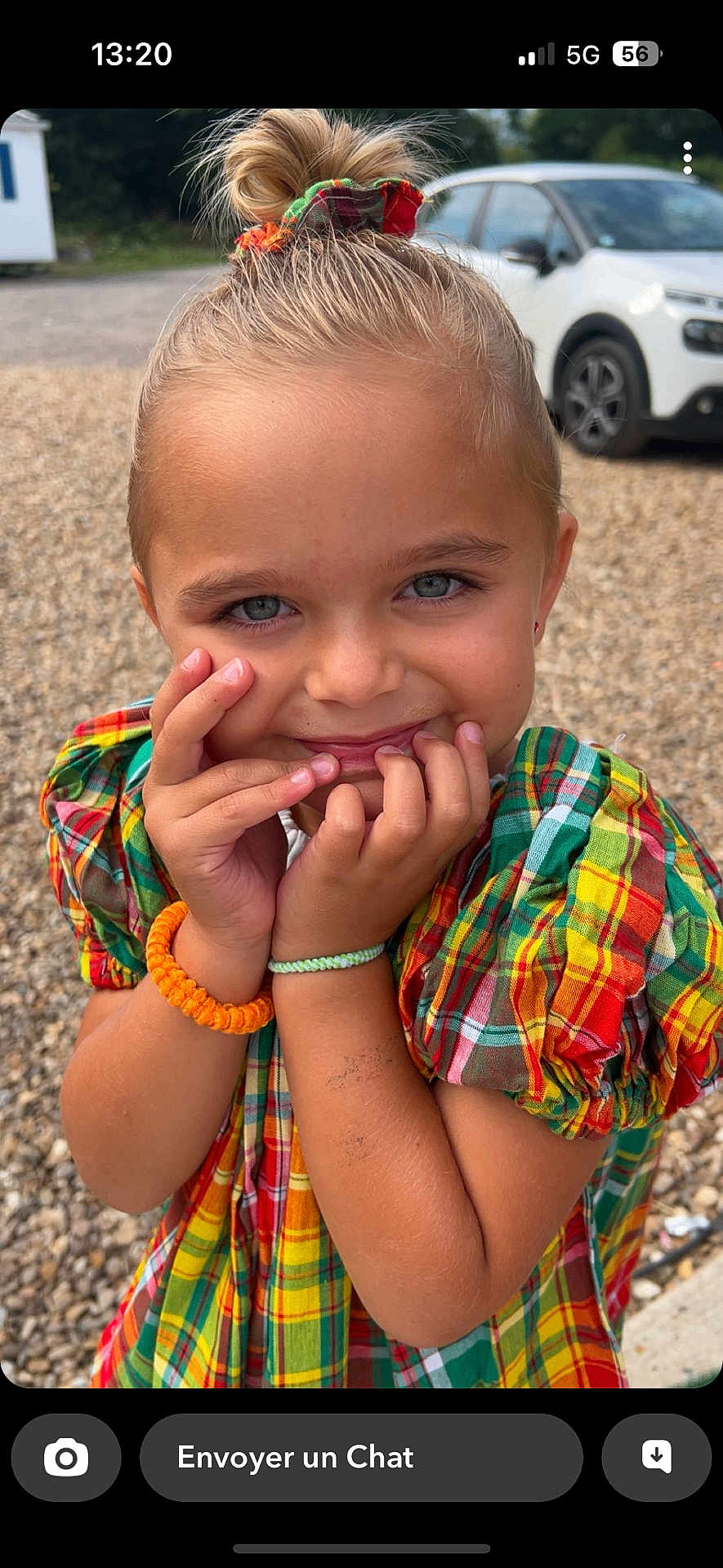 Romy participe au concours pour gagner de l'argent avec cette photo : child, smiling, outdoor, plaid_dress, colorful, hair_scrunchie, hands, face, blue_eyes, happy, young, girl, gravel, car, casual, cute, portrait, sunlight, accessories, playful