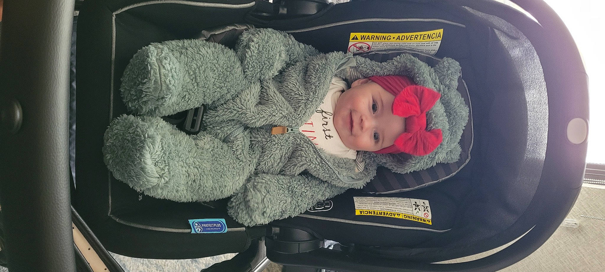 Isla is registered to the contest to win money with this photo: auto_part, baby, baby_carriage, baby_products, baby_safety, baby_sleeping, baby_toddler_clothing, bag, car_seat, child, comfort, headgear, headwear, joy, lap, motor_vehicle, person, plant, sitting, toddler
