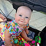 baby, child, smiling, blue_eyes, colorful_dress, toys, plush_toy, playpen, stroller, mesh, cute, infant, happy, indoors, soft_light, sitting, hands, face, person, portrait