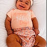 Alison joined the competition — help win amazing prizes! baby, infant, smiling, headband, peach_color, shirt, happy_fathers_day, flower_print, diaper_cover, cushion, white_background, cute, chubby_arms, chubby_legs, portrait, indoors, child, person, happy, lying_down