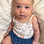 Laila is registered to the contest to win money with this photo: baby, infant, child, face, eyes, skin, clothing, tank_top, shorts, blue, floral, pattern, blanket, soft, cozy, sitting, cute, portrait, indoors, young