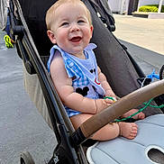 Colson is registered to the contest to win money with this photo: baby, stroller, smile, child, outdoor, sunlight, happy, infant, clothing, bib, seat, footwear, toy, hand, face, expression, person, park, daylight, greenery