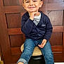 Sohann a rejoint le concours — aidez-le/la à gagner de superbes lots ! boots, cardigan, casual_clothing, child, cozy, cute, face, fashion, floor, happy, indoor, jeans, person, portrait, sitting, smiling, stool, striped_shirt, wooden_background, young_boy